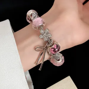 Close-up of sweet charm bracelet with pink glass beads and diamond flower bow charms.