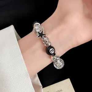 Close-up of a stylish glass bead bracelet with star and number 8 charms on a wrist