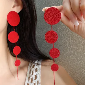 Red textured multi-circle long drop earrings shown on model and held in hand