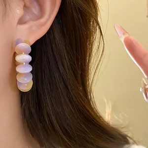 Detailed view of sweet resin hoop earrings with purple and yellow beads worn on an ear