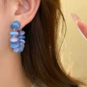 Detailed view of blue and purple resin bead hoop earrings with a dreamy cat eye luster.