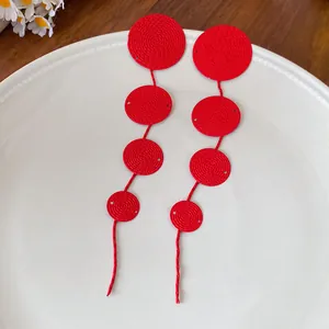 Detailed macro view showing the unique textured pattern of these red circular tassel earrings