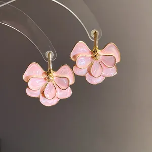 Detailed macro view of elegant pink enamel flower earrings with gold-toned leaf edges