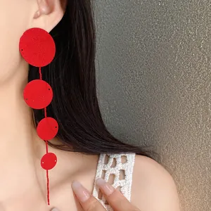 Close-up shot of elegant red circular textured tassel earrings worn by a female model