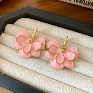 Close-up of pink flower earrings with gold petals in a white velvet jewelry box