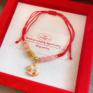 Close-up detail of red woven bracelet with pink beads and rocking horse pendant