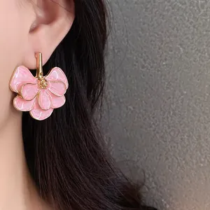 Close-up macro view of elegant pink ginkgo leaf flower shaped earrings worn on the ear