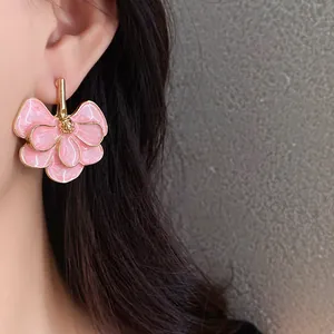 Elegant pink flower ginkgo leaf stud earrings with gold trim worn by an Asian model