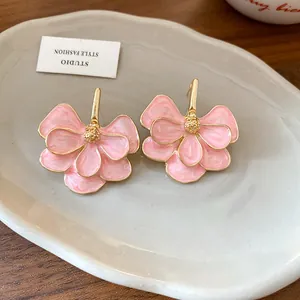 Close-up view of elegant pink flower stud earrings with gold trim on a white plate