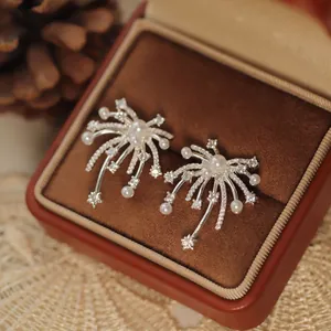 Close-up view of elegant zircon and pearl firework stud earrings in a luxury box