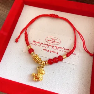 Detail of red woven bracelet with gold horse charm and red beads in gift box