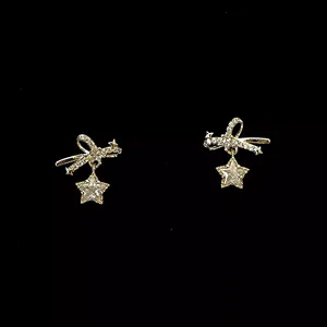 Detail showing elegant gold bowknot earrings with sparkling zircon star charms.