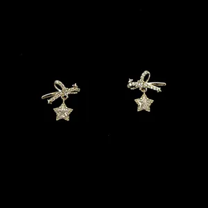 Close-up of elegant gold-tone bow and dangling star earrings with sparkling zircons