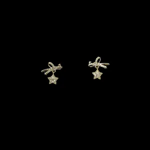 Detailed macro view of gold bow earrings with shimmering zircon star pendants