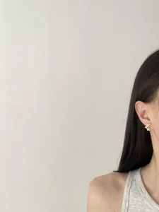 Detailed view of elegant gold-toned bow and star stud earrings worn by a model