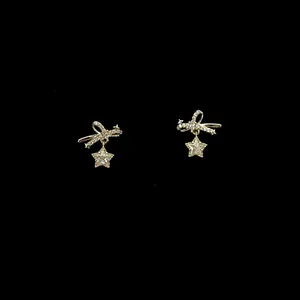 Detailed view of elegant gold bow earrings featuring sparkling zircon star dangles on black