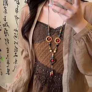 Close-up detail of ethnic bohemian necklace with colorful beads and wooden rings on model