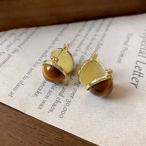 Nahaufnahme der beidseitigen runden Ohrringe mit Goldtextur und braunem Tigeraugenstein