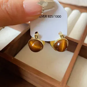 Elegante goldene Maillard-Ohrringe mit braunen Katzenaugen auf silberner Karte.