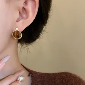 Detaillierte Nahaufnahme von runden braunen Klappohrringen im Vintage-Stil am Ohr eines Models