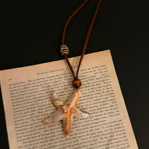 Close-up of a realistic starfish pendant necklace resting on vintage book paper.