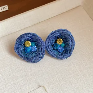 Detaillierte Nahaufnahme handgefertigter blauer gewebter Blumenohrringe mit bunten Kristallen