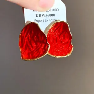 Eleganti orecchini a lobo ovali irregolari in smalto rosso con bordo dorato e ago in argento.