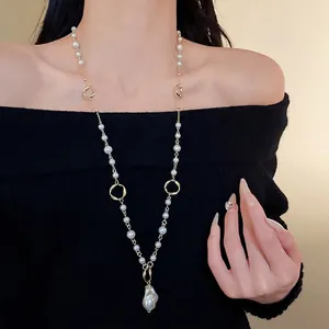 Elegant long sweater necklace with irregular faux pearl pendant and gold-tone links.