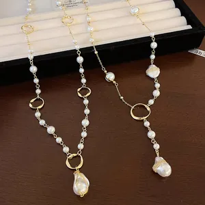 Detailed view of irregular baroque pearl pendant wrapped in gold wire on long necklace.