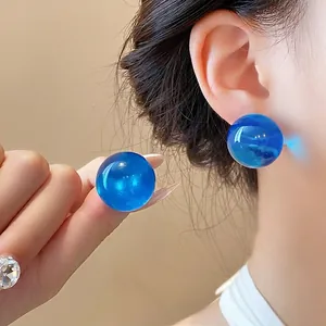 Eleganti orecchini a lobo in resina sferica blu per donna mostrati sull'orecchio di una modella