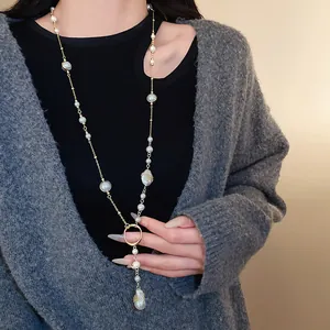 Close-up of irregular artificial pearl pendant and golden link chain sweater necklace