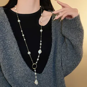 Detailed view of an irregular faux pearl long sweater necklace worn over a grey cardigan