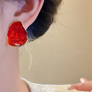 Primo piano di un orecchino a perno in smalto rosso di forma ovale irregolare