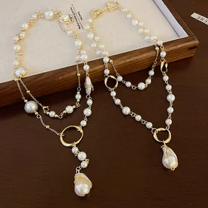Close-up of elegant irregular faux pearl pendant necklace with vintage gold chain