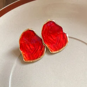 Primo piano orecchini smalto rosso forma ovale irregolare con bordo dorato