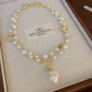 Detail view of a vintage-style gold-toned necklace featuring irregular faux pearl pendant.