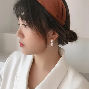Close-up of elegant double pearl drop earrings with silver needles on model