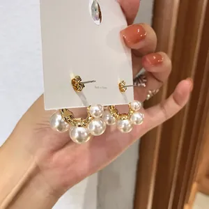 Close-up detail of elegant gold hoop earrings adorned with clusters of white pearls.