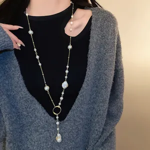 Elegant long sweater chain necklace with irregular white faux pearls on grey knitwear.