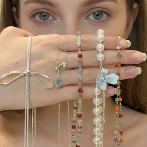 Elegant aesthetic jewelry set featuring pearl and bow necklaces displayed on hand in soft light