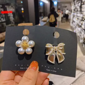 Close-up of elegant pearl flower and golden bow brooches on black jewelry cards