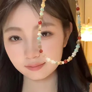 Close-up of a colorful beaded necklace featuring red, turquoise, and gold beads on a model