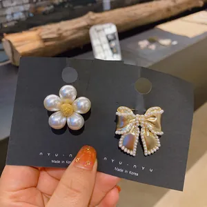 Macro view of elegant pearl flower and golden bow brooches displayed on black jewelry cards
