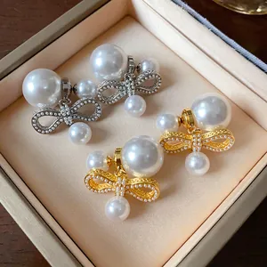 Dettaglio di orecchini a fiocco in oro e argento con grandi perle in una scatola regalo