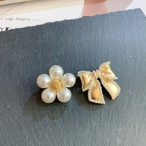 Elegant vintage jewelry detail: pearl flower and golden bow brooches on dark stone