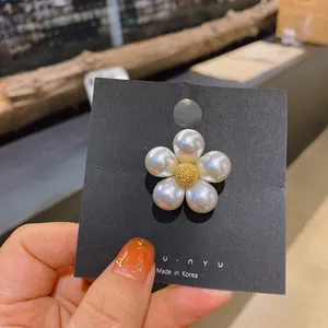 Close-up detail of an elegant pearl flower brooch pinned on a black display card