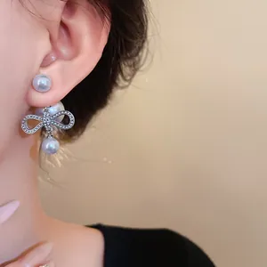 Primo piano di eleganti orecchini a fiocco argento con perle finte pendenti sull'orecchio