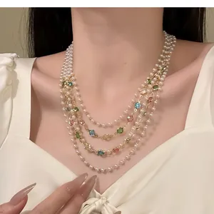 Close-up detail of multi-layered pearl necklace with colorful gemstones on model neck