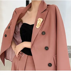 Detailed macro view of a vintage gold abstract face brooch pinned on a pink blazer