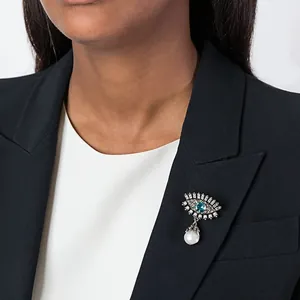 Elegant evil eye brooch with blue crystal and pearl drop on a black blazer